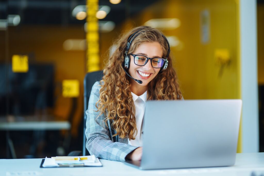 Call center agent with headset working on support hotline in modern office. Video conference.