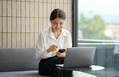 Beautiful Asian woman using smartphone to check work contact customers, answer chats, complete trans