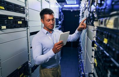 IT technician consulting tablet computer during preventive maintenance